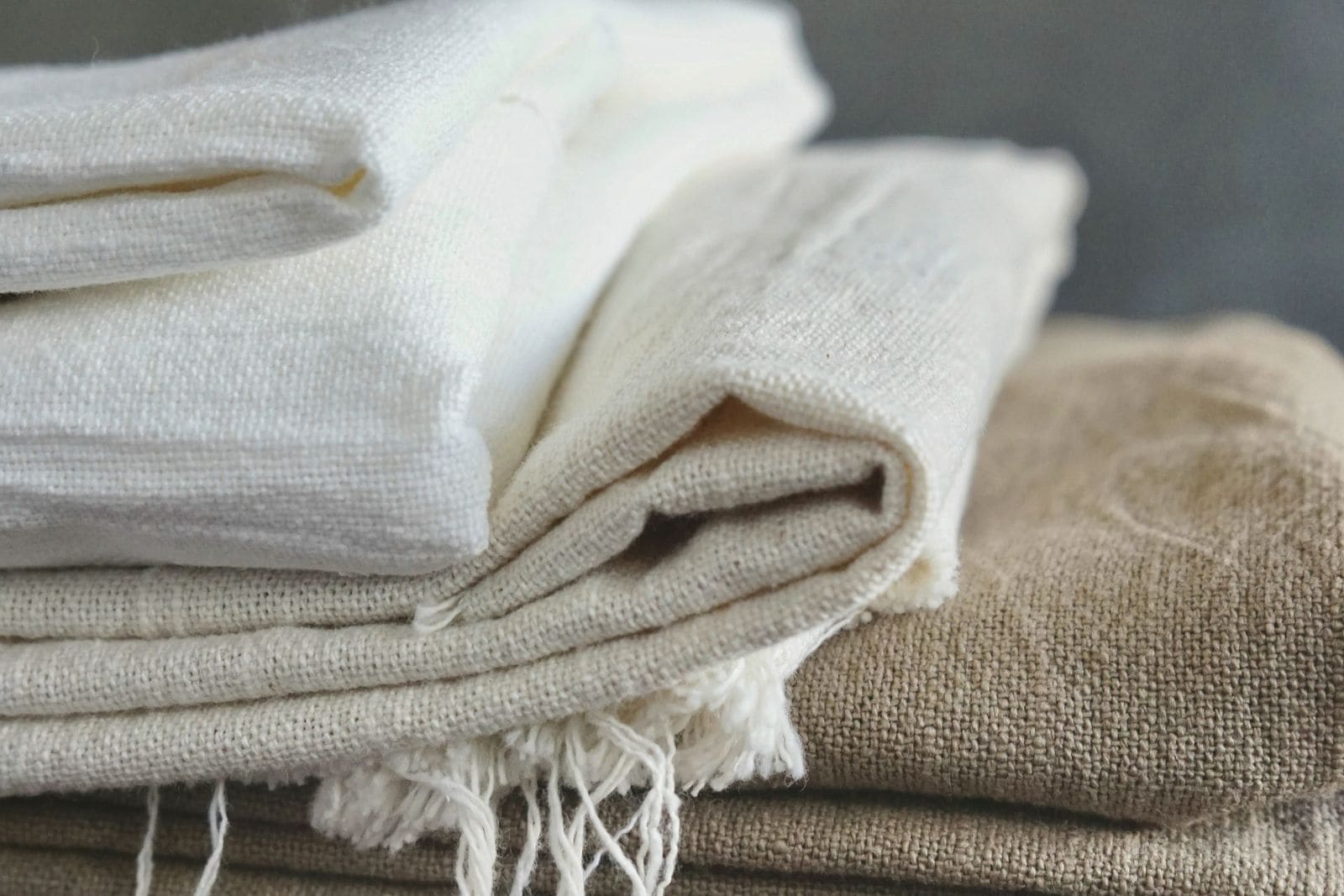 Folded natural linen and cotton cloths stacked on a wooden bench